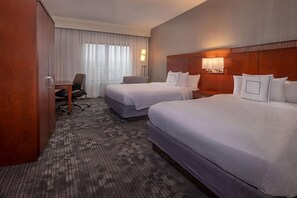 Ein Hotelzimmer mit zwei Betten, einem Schreibtisch und einem Stuhl.