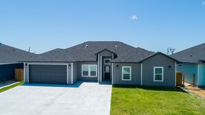 A modern two-story house with a garage, a front door, and a small porch.