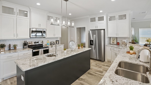 A modern kitchen with white cabinets, stainless steel appliances, a granite countertop, and a black island.