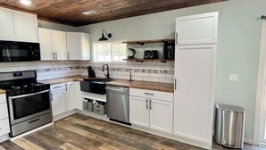 Una cocina moderna con gabinetes blancos, electrodomésticos de acero inoxidable y techo de madera.