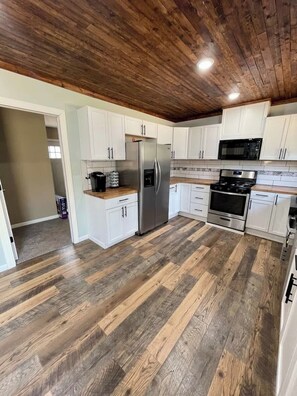 A kitchen with white cabinets, stainless steel appliances, and a wooden floor.