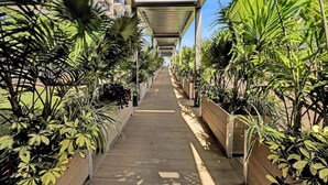 Une allée couverte, bordée de jardinières et flanquée de bâtiments de part et d’autre.