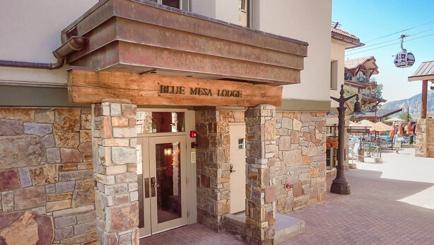 La entrada al Blue Mesa Lodge, con pilares de piedra y un letrero de madera sobre la puerta.
