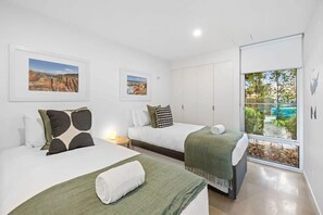 A hotel room with two beds, a large window with a view, and artwork on the walls.