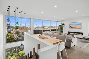 A modern living room with a curved white counter, a fireplace, and large windows offering a view of the neighborhood.