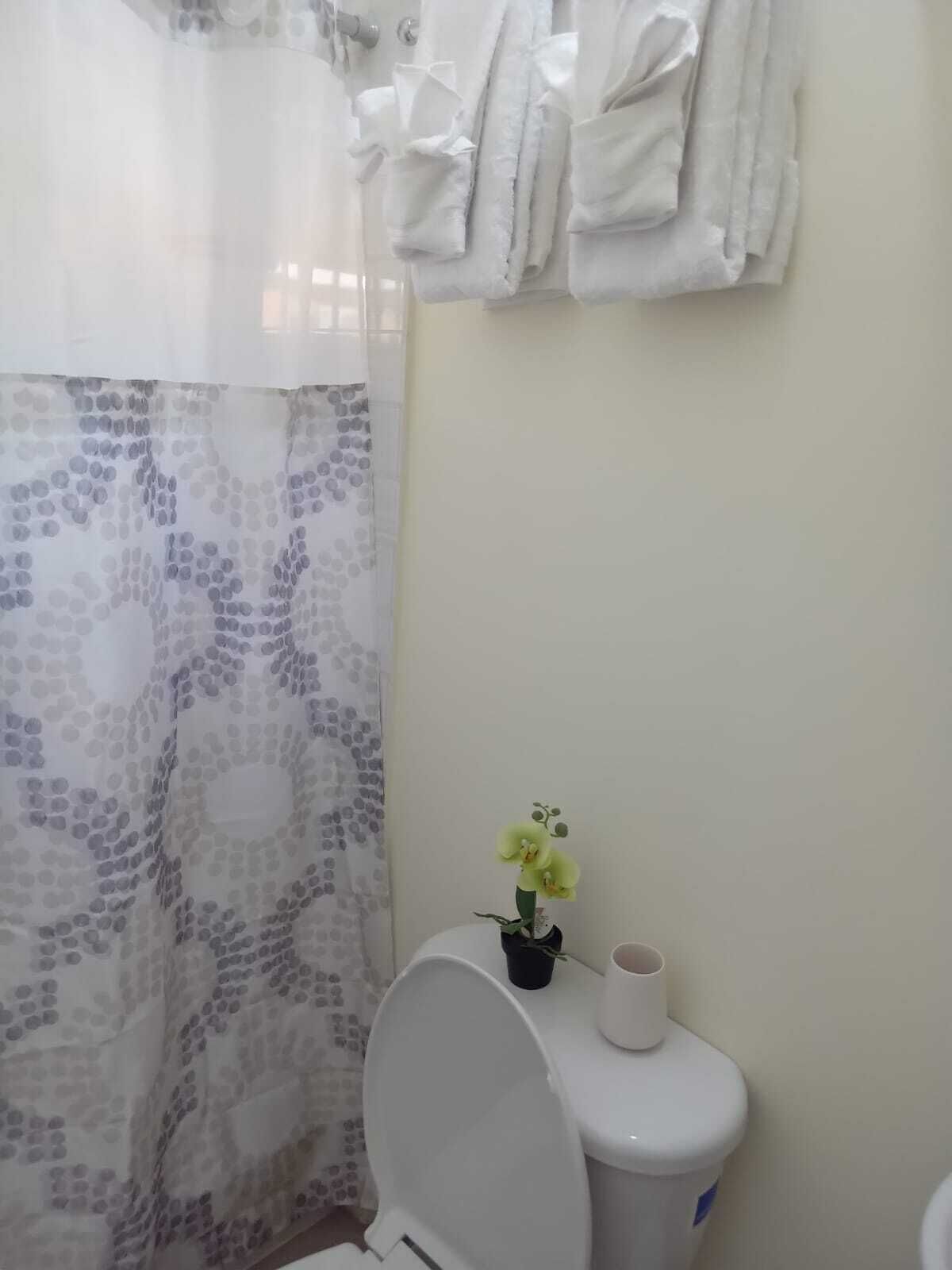 A bathroom with a toilet, a shower curtain, and a towel rack with towels.
