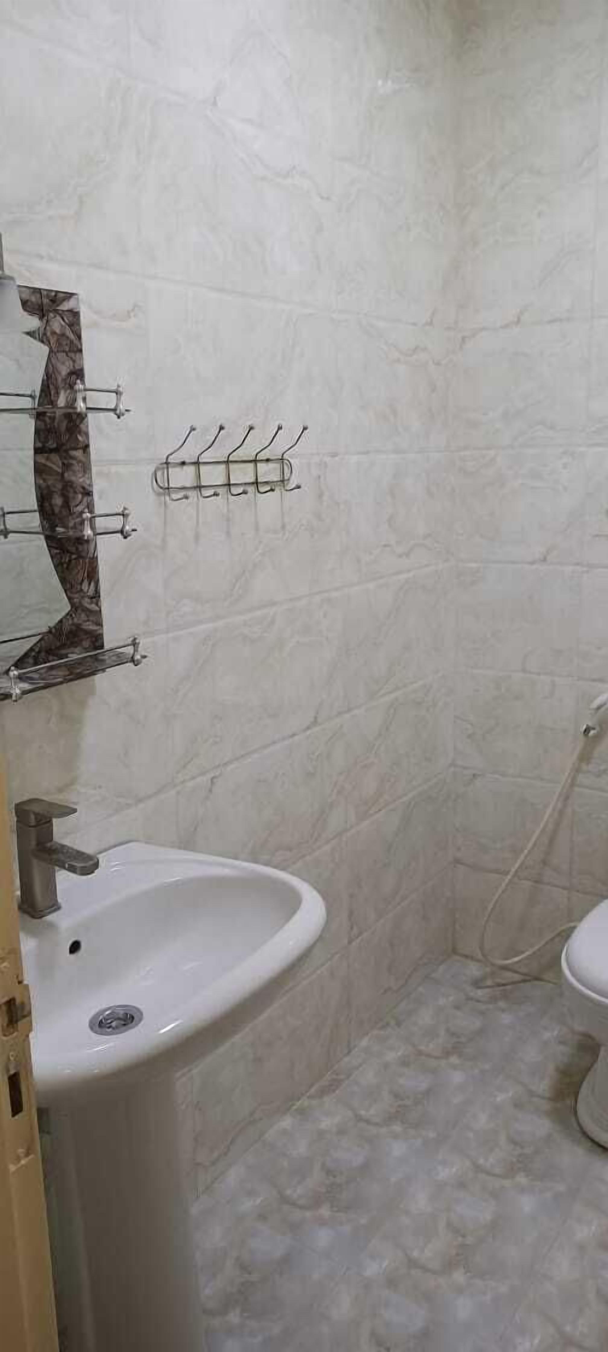 Une salle de bain avec un lavabo blanc, des toilettes et une douche. Il y a des porte-serviettes au mur.