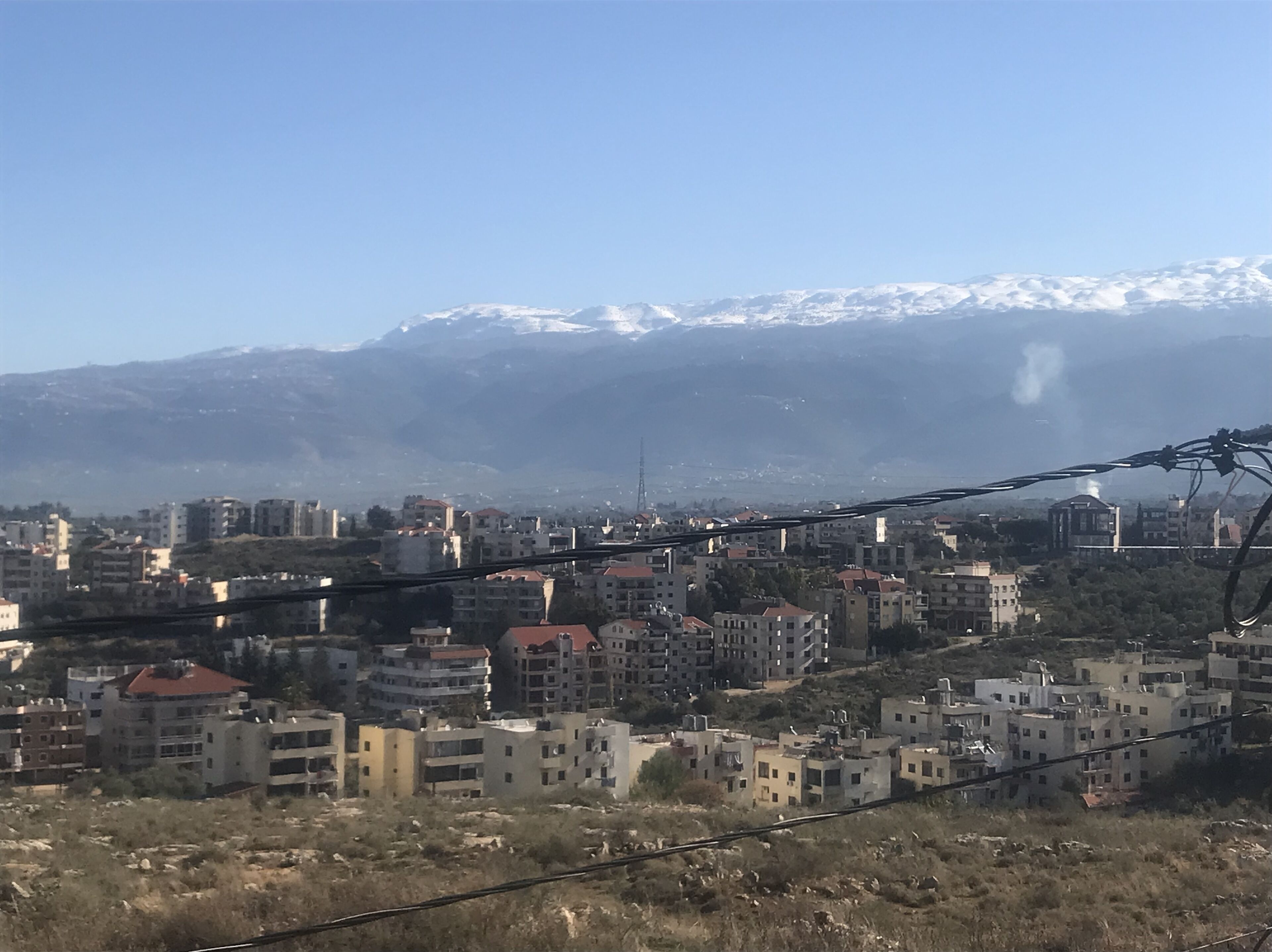 Paesaggio urbano con edifici e una catena montuosa sullo sfondo.