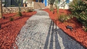 Un chemin menant à une maison avec un mur en pierre et une porte bleue.