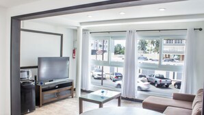 Een moderne woonkamer met een flatscreen televisie, een glazen salontafel en een bank.