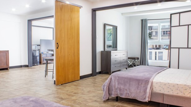 Een moderne slaapkamer met een bed, een dressoir, een bureau en een stoel.