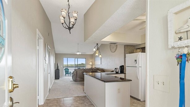 A modern kitchen with a central island, white cabinetry, and a view to the outside. - New Intracoastal Oasis | Flagler Beach | Intracoastal Views | Walk To The Beach | Solar Heated Pool (Flagler Beach)