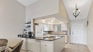 A spacious kitchen with a large island, white cabinetry, and a chandelier. - New Intracoastal Oasis | Flagler Beach | Intracoastal Views | Walk To The Beach | Solar Heated Pool (Flagler Beach)