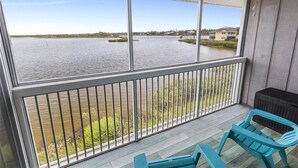 A balcony with a view of a lake, a railing, and two blue chairs. - New Intracoastal Oasis | Flagler Beach | Intracoastal Views | Walk To The Beach | Solar Heated Pool (Flagler Beach)