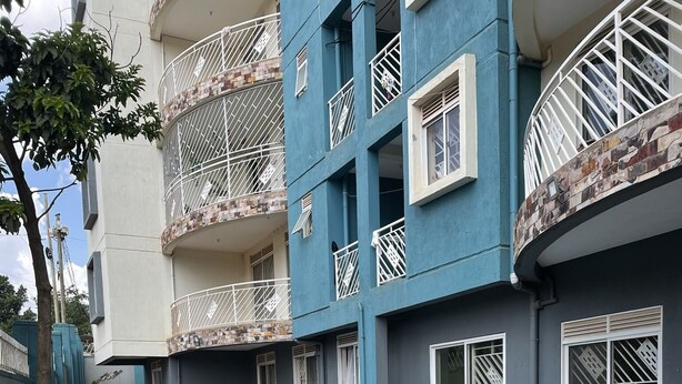 A residential building with a swimming pool, balconies with metal railings, and a small garden area. - Fully-furnished 2BR/2BA Condo in Kampala with WiFi, gym, pool, Gated Community (Kampala)