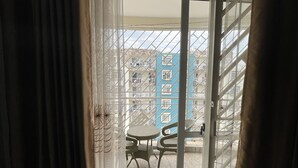 A room with a sliding glass door leading to an outdoor area with a blue building and a table with chairs. - Fully-furnished 2BR/2BA Condo in Kampala with WiFi, gym, pool, Gated Community (Kampala)