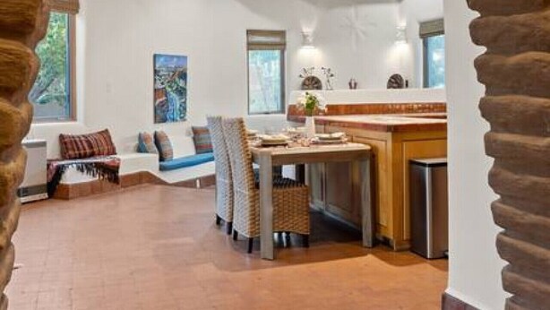 A spacious living area with a rustic stone archway, a wooden dining table, and a comfortable seating arrangement. - Upscale Home In North Hills (Santa Fe)