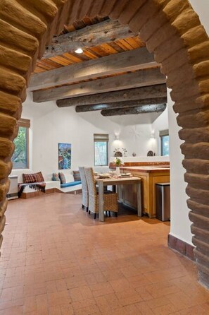 A spacious living area with a rustic stone archway, a wooden dining table, and a comfortable seating arrangement. - Upscale Home In North Hills (Santa Fe)