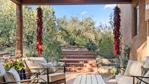 An outdoor patio with a seating area, a small table, and a staircase leading to a higher level. - Upscale Home In North Hills (Santa Fe)