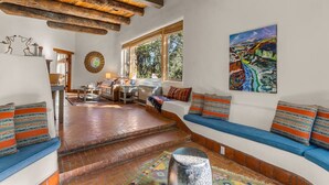 A spacious living room with a fireplace, a large window, and a colorful painting on the wall. - Upscale Home In North Hills (Santa Fe)