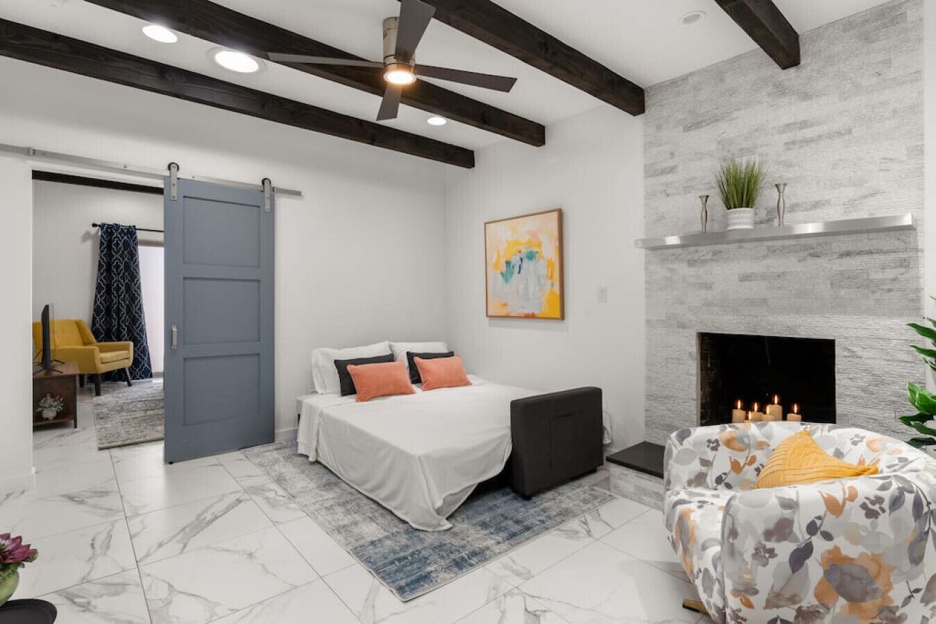 Une chambre moderne avec un lit, un canapé, une cheminée et un ventilateur de plafond.