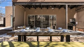 An outdoor dining area with a table set for four, a grill, and a covered seating area. - Modern & Cozy Santa Fe Escape (Santa Fe)