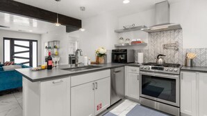 A modern kitchen with a central island, stainless steel appliances, and a herringbone-patterned backsplash. - Modern & Cozy Santa Fe Escape (Santa Fe)