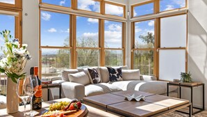 Ein modernes Wohnzimmer mit einer Couch, einem Couchtisch und Blick ins Freie durch große Fenster.