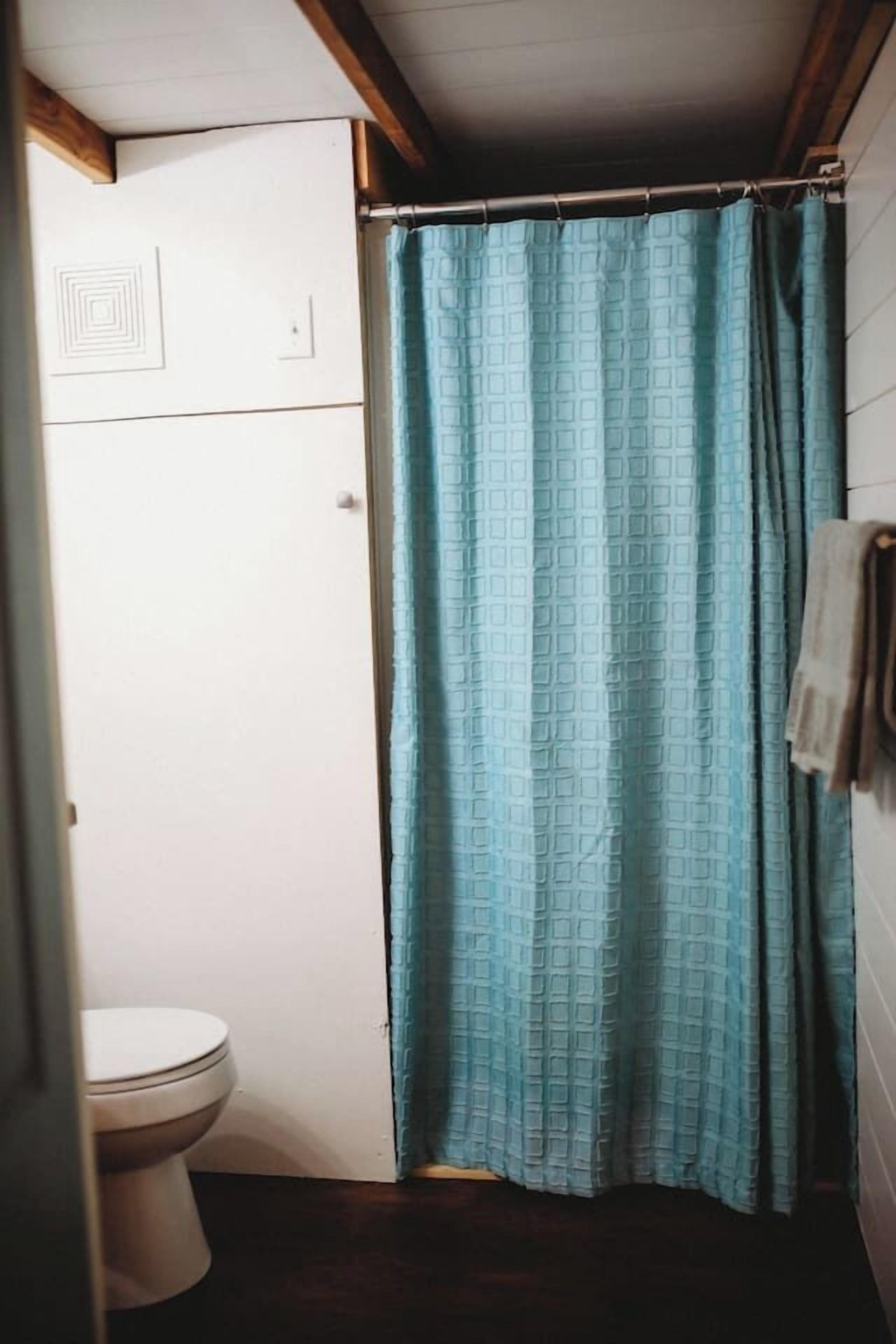 A small bathroom with a toilet, a shower curtain, and a towel hanging on the wall.