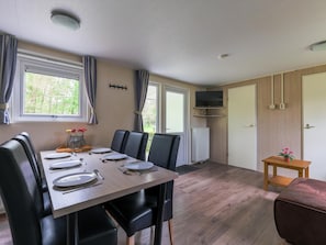 Un coin repas avec une table dressée pour quatre personnes, des chaises noires, une table en bois et un radiateur.