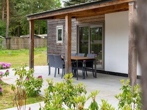 Ein überdachter Patio-Bereich mit Holztisch und -stühlen, einer Glasschiebetür und einem Schild mit der Nummer 588.