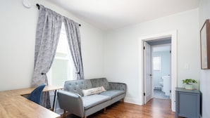 Una habitación con un sofá gris, una mesa de madera y una puerta que da a otra habitación.