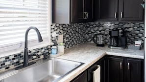 Una cocina moderna con un lavamanos de acero inoxidable, armarios negros y un salpicadero de azulejos.