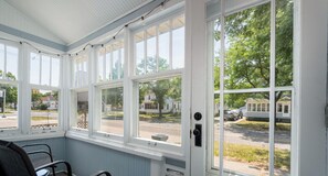 Ein Zimmer mit großen Fenstern, einer Tür und zwei Stühlen.