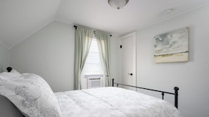 A bedroom with a bed, a window with curtains, an air conditioning unit, and a painting on the wall. - Holland Hideaway (Holland)