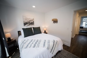 Camera da letto con un letto grande, un comodino, una lampada a muro e una decorazione a forma di orso.