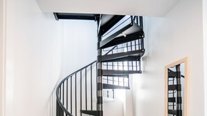A modern interior with a black spiral staircase, wooden flooring, and a white wall with a mirror. - Rooftop Condo in TC w/ Bay Views (Traverse City)