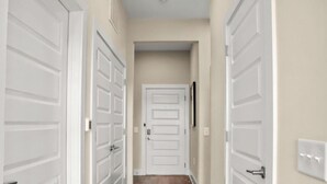 Un pasillo con puertas dobles blancas, paredes color beige y un interruptor de luz en la pared.