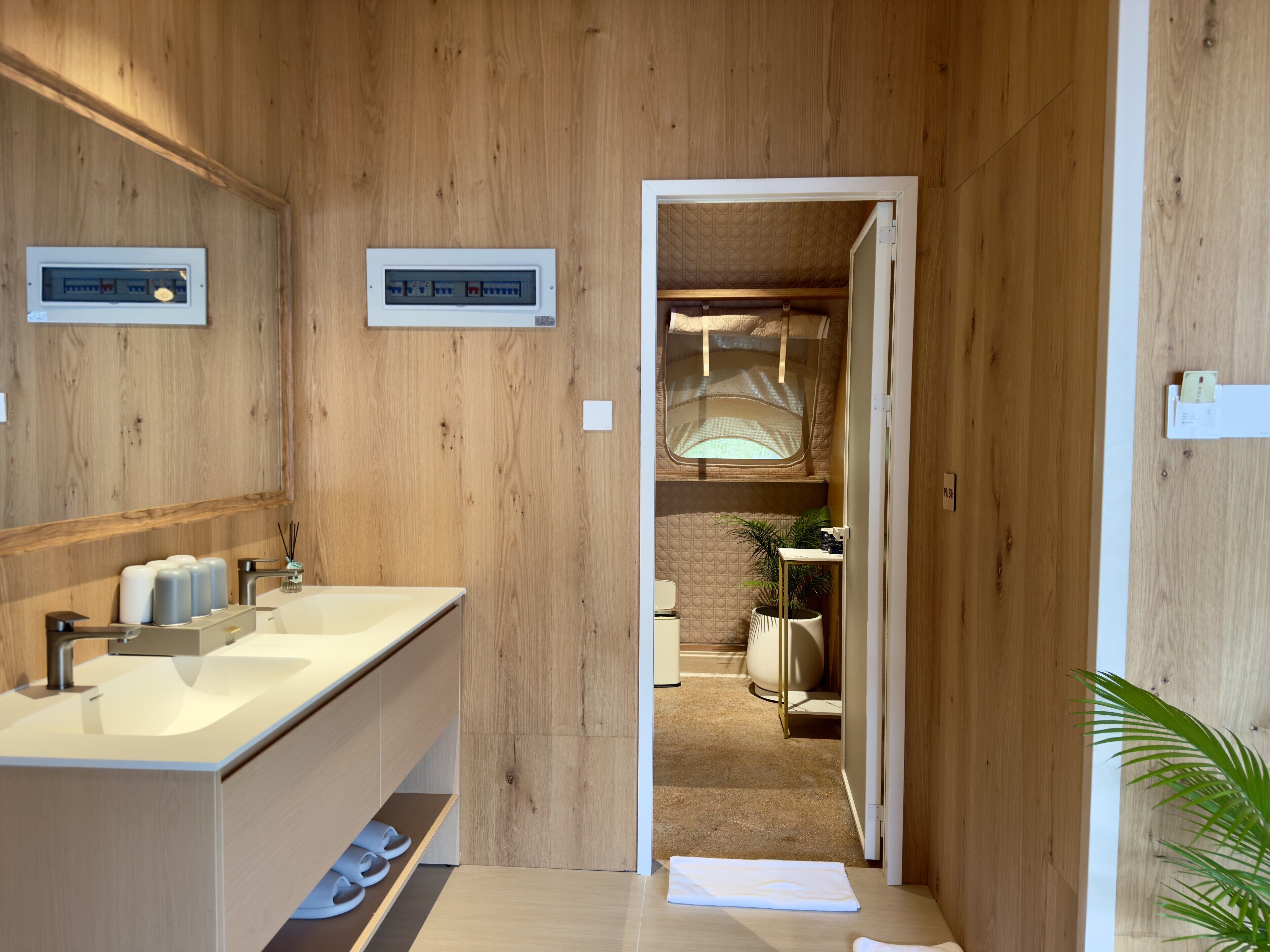 A wooden bathroom with a double sink, towel rack, and a small window.