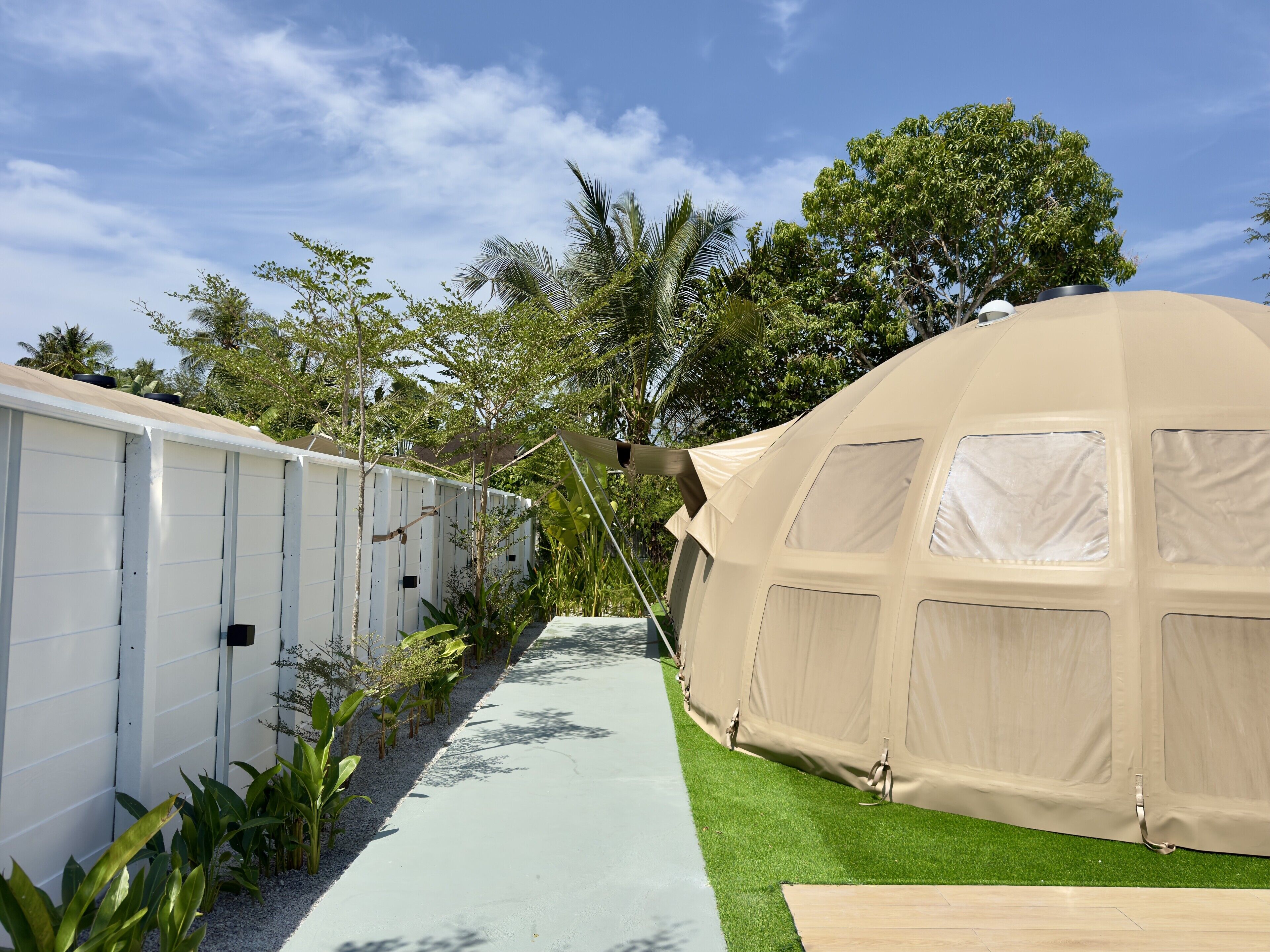 A tented accommodation with a pathway leading to it, surrounded by greenery and trees.
