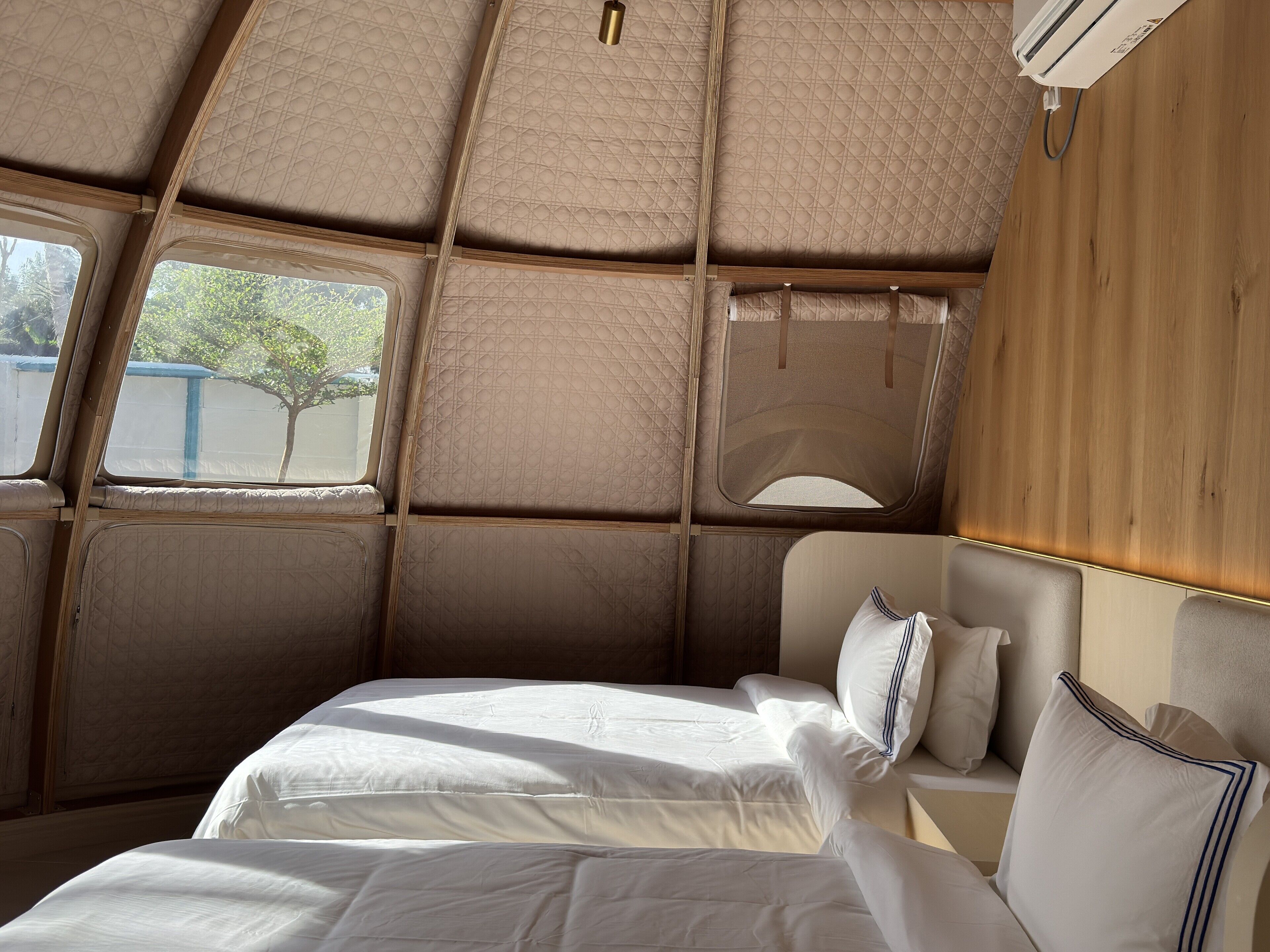 A cozy interior with a bed, a window, and a wooden panel wall.