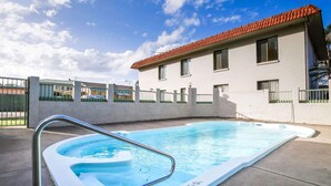 Une piscine avec un escalier en métal, entourée d’une terrasse en béton.