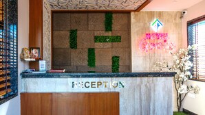 A hotel reception area with a reception desk labeled "RECEPTION" and a neon sign for "HOTEL GEMS".