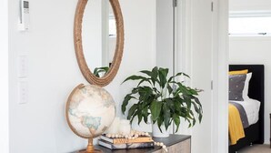 A hallway with a wooden cabinet, a globe, a mirror, and a potted plant. - Poolside Stay with City Views | Close to the Redwoods for Forest Adventures (Rotorua)