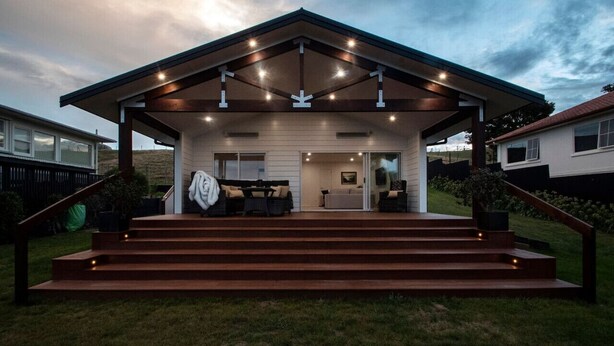 A modern house with a covered porch, outdoor seating, and a staircase leading to the entrance. - Poolside Stay with City Views | Close to the Redwoods for Forest Adventures (Rotorua)