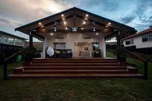 Una casa moderna con un porche cubierto, mobiliario exterior y una escalera que conduce a la entrada.