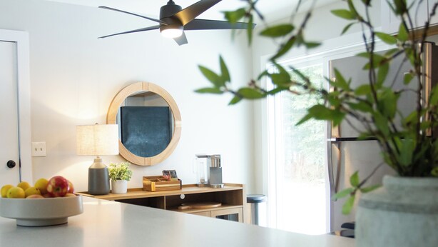 Eine Küche mit Deckenventilator, Obstschale, Kaffeemaschine und Topfpflanze.