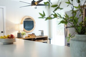 Una cocina con ventilador de techo, un bol de fruta, una cafetera y una planta en maceta.