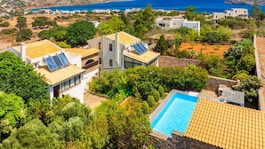 A residential area with modern houses, a swimming pool, and a view of the sea. - Villa Elounda Plaka in Plaka (Agios Nikolaos)