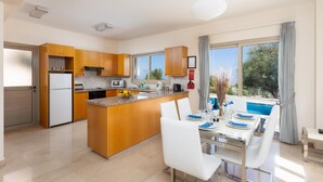 Une cuisine moderne avec des meubles en bois, un îlot central et un coin repas avec une table dressée pour deux personnes.